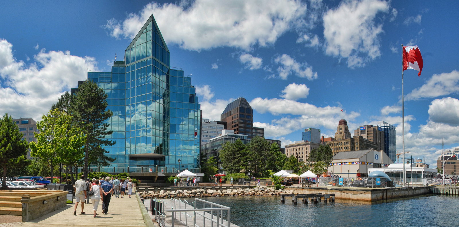 Large cruise ship docked at a modern pier in Halifax, Nova Scotia, with city buildings in the background.