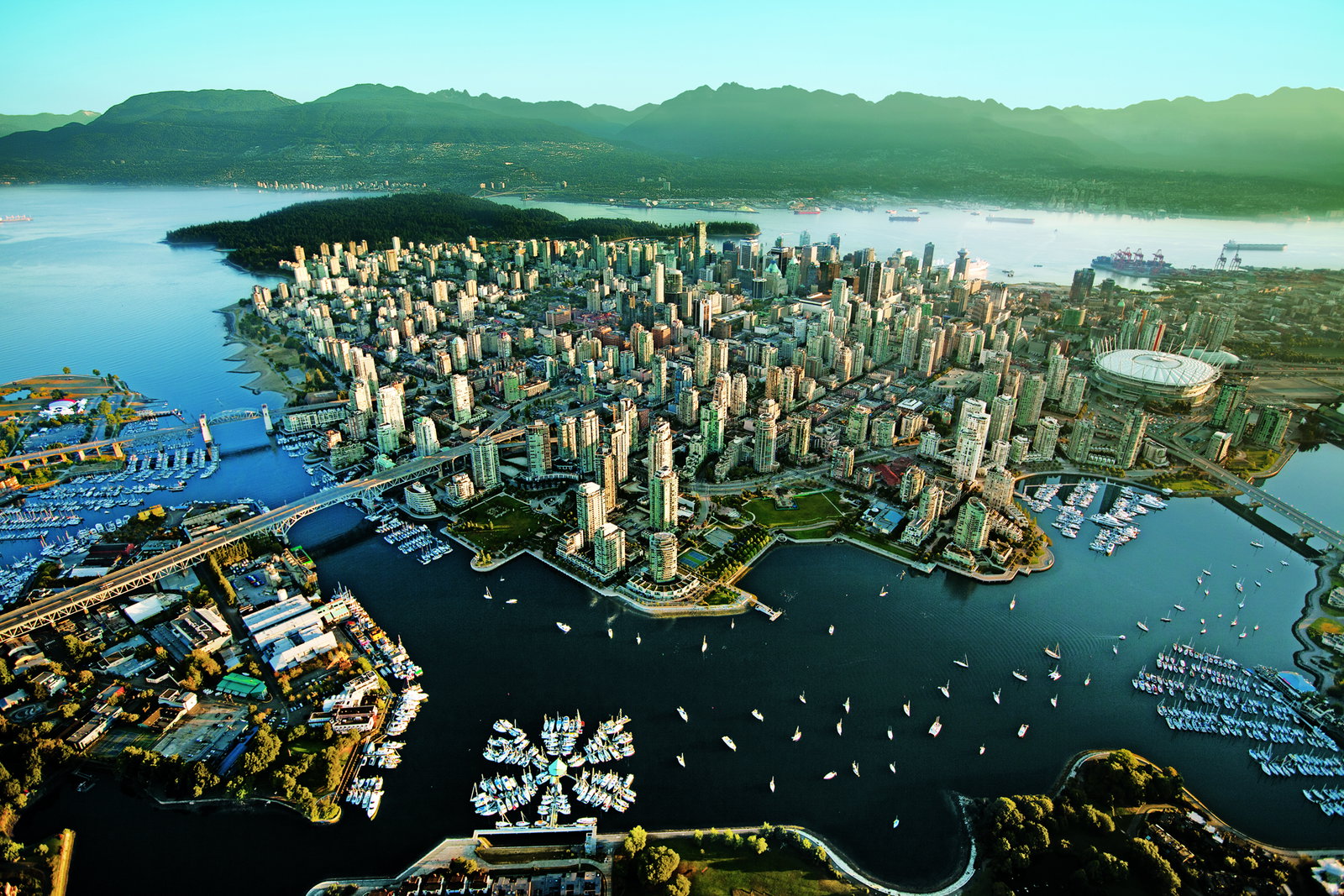 Cruise ship docked in Vancouver harbor with city skyline and mountains.