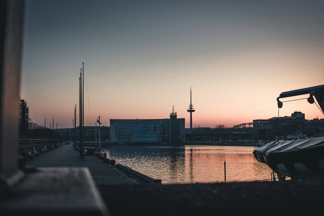 A cruise ship docked in Kiel, Germany, with city buildings and a canal in the background.