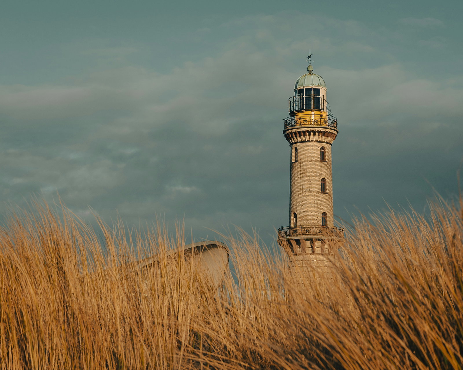 A large cruise ship docked in a bustling Warnemünde port with a lighthouse in the background.