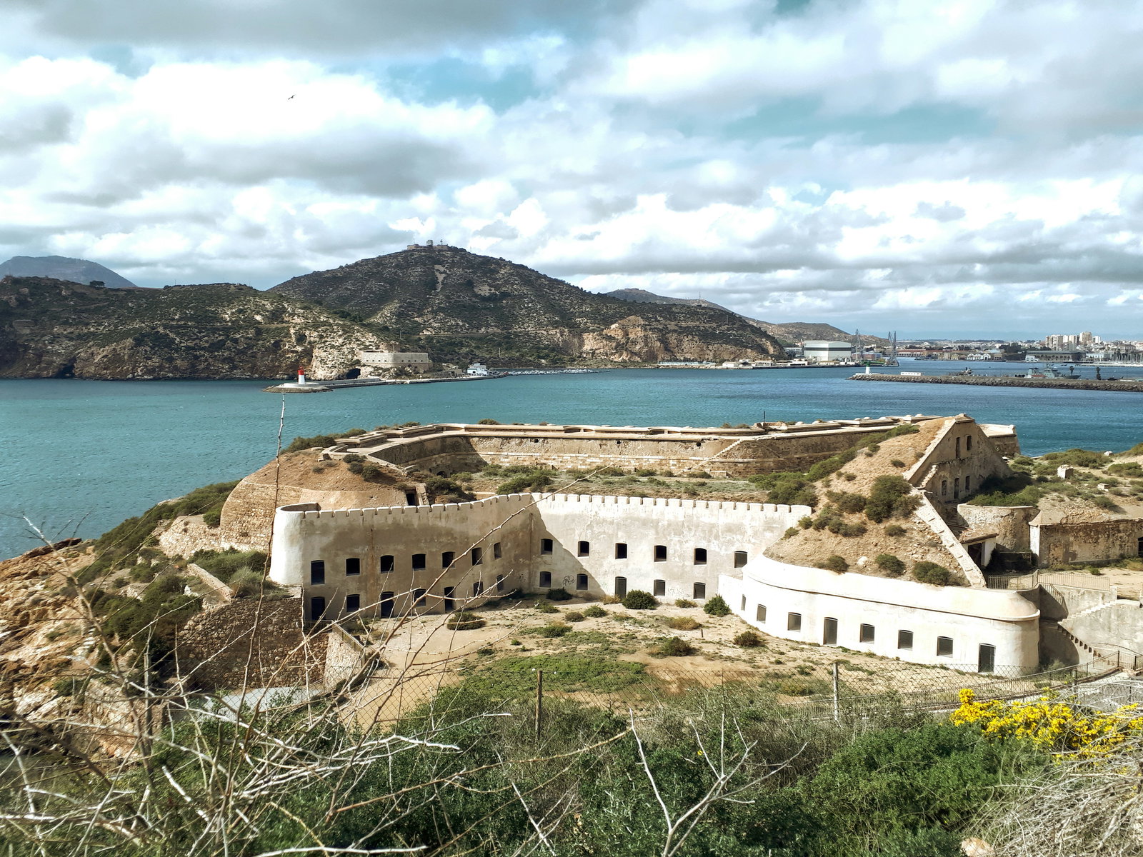Historic harbor of Cartagena, Spain, with ancient buildings and a cruise ship docked.