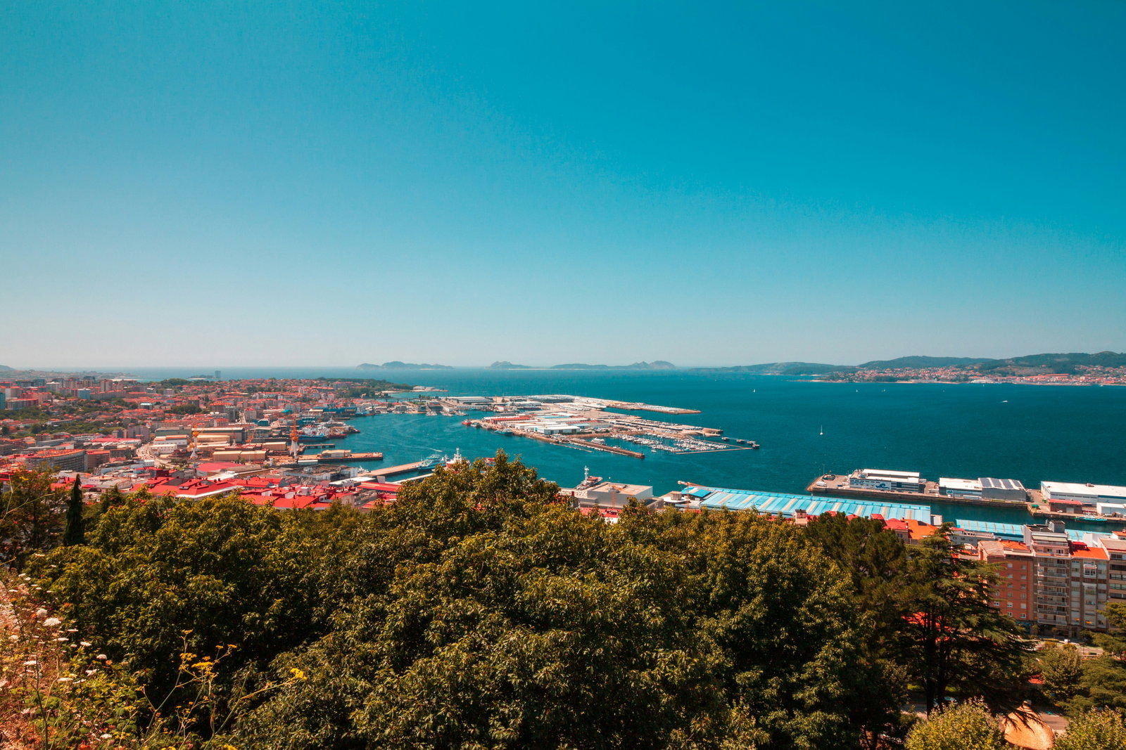Cruise ship docked in Vigo, Spain, with the historic city and hills in the background