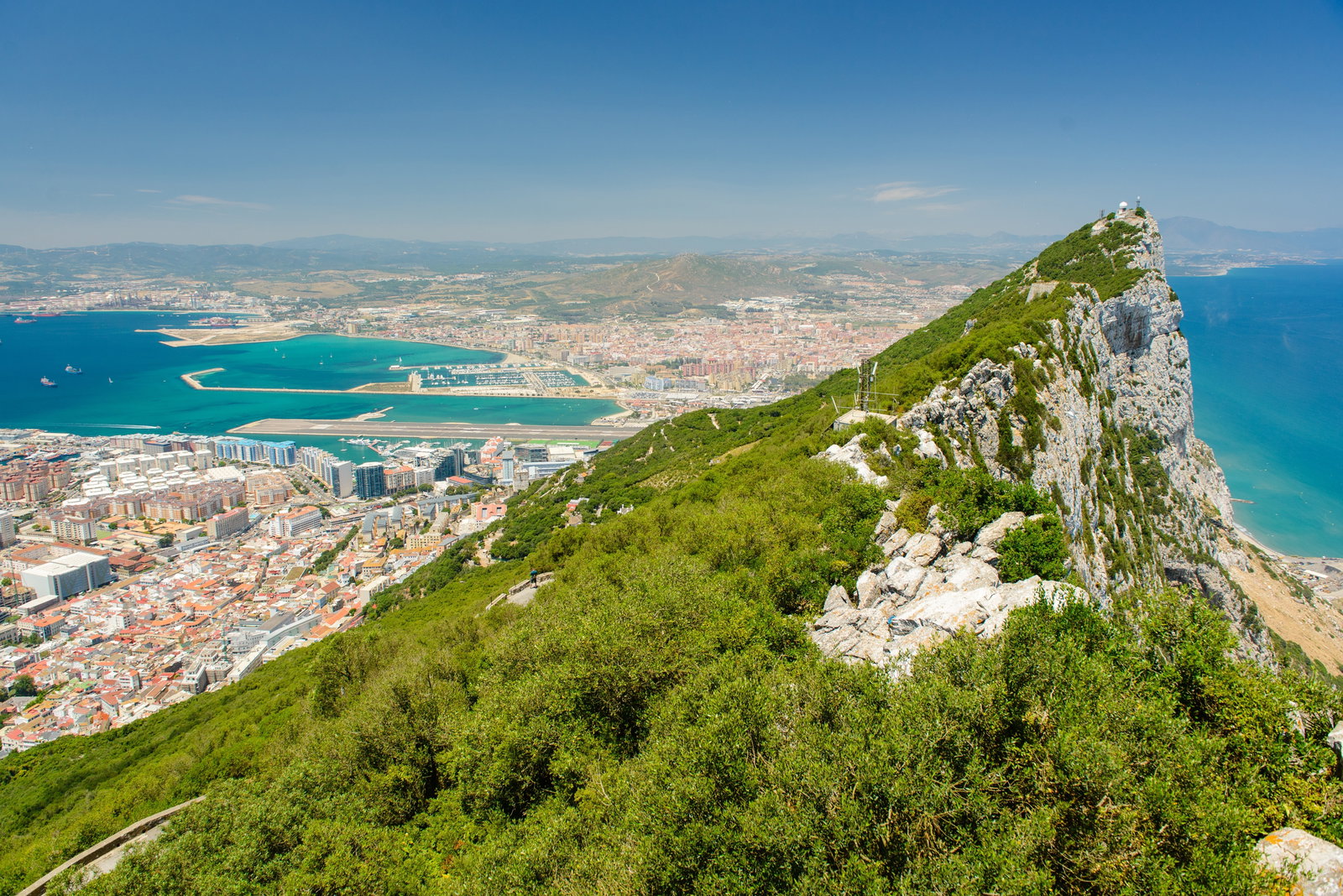 View of the Rock of Gibraltar rising from the sea, with buildings at its base.