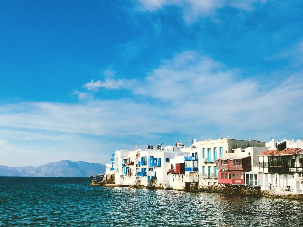 Whitewashed buildings and narrow streets in Mykonos Town under a clear blue sky.
