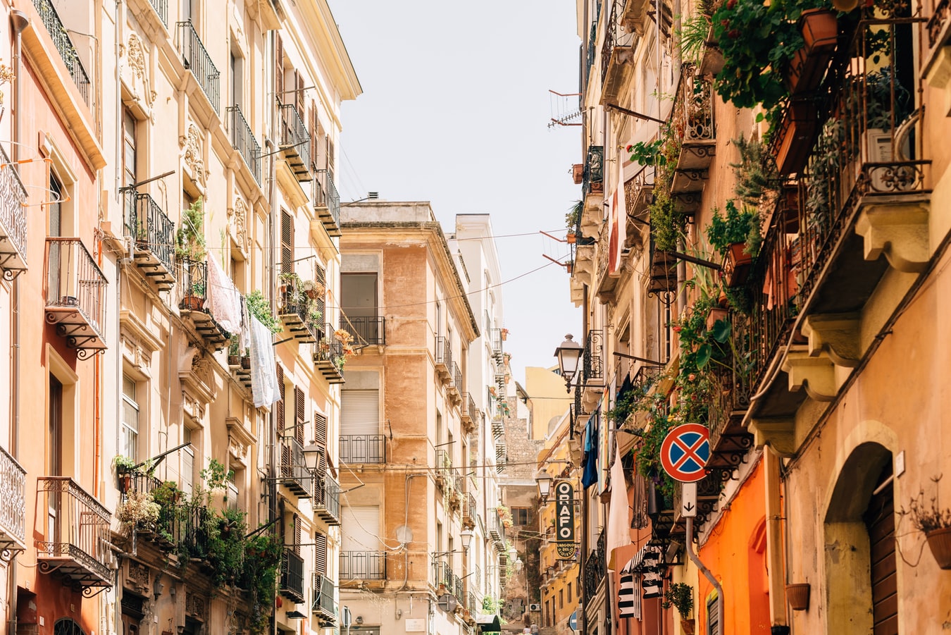 Historic buildings and a bustling waterfront in Cagliari, Sardinia, under a sunny sky.