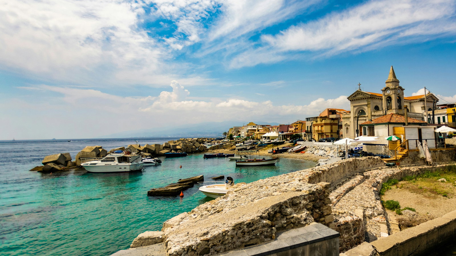Historic Messina harbor with a cruise ship docked and the city skyline in the background.