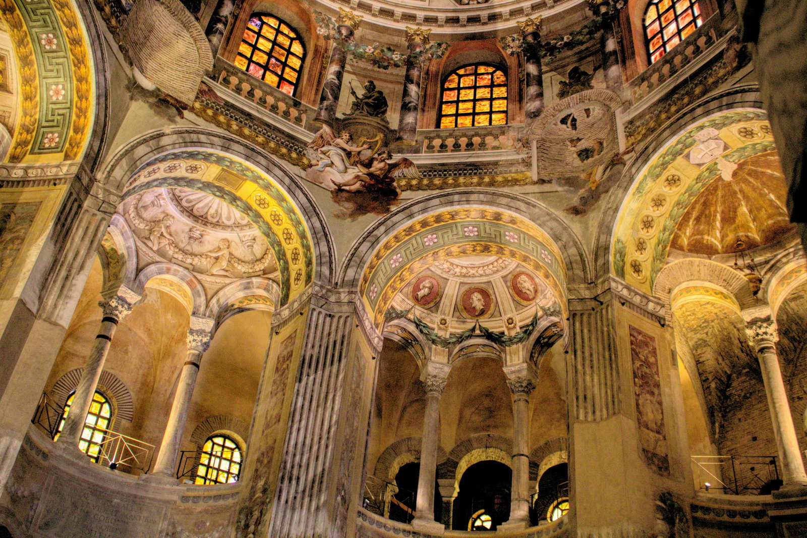 A quiet Italian city street with historic brick buildings and a glimpse of an ancient mosaic.