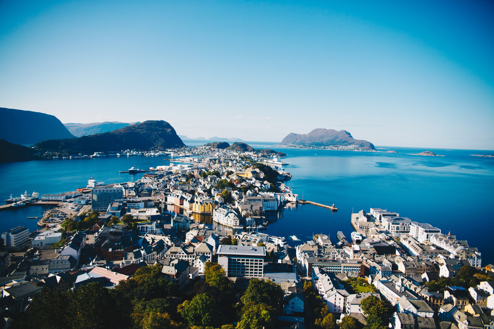 View of Ålesund, Norway, with colorful Art Nouveau buildings along a canal and mountains.