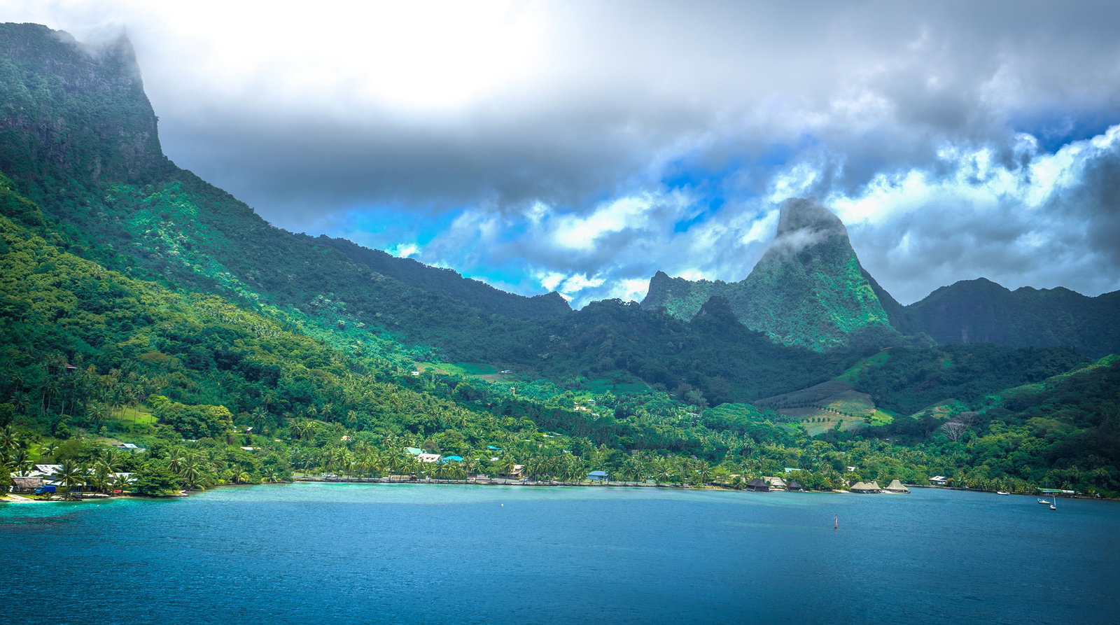 Lush green volcanic mountains rise above a clear turquoise lagoon in Moorea