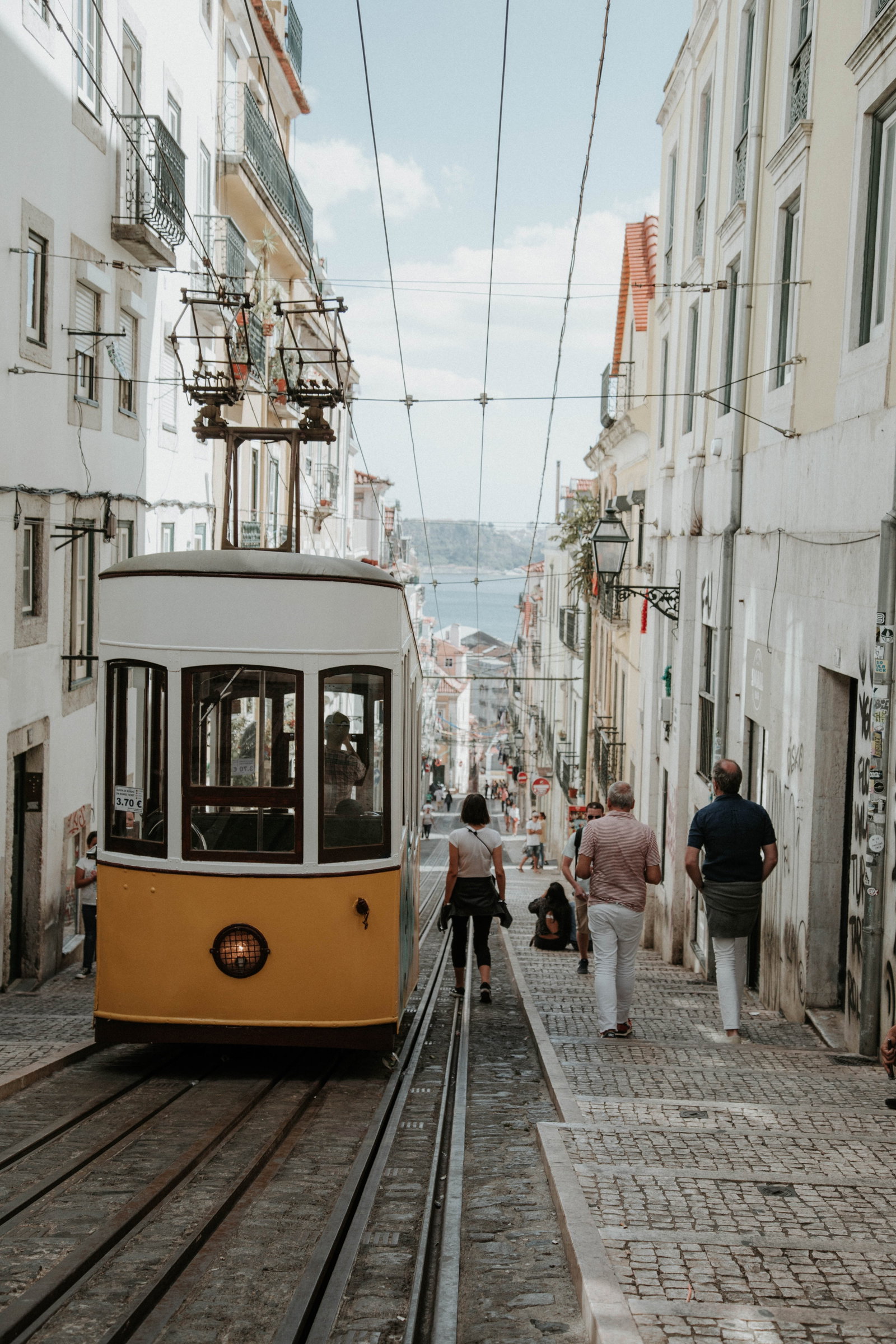 PTLIS Lisbon thee person walking near white and orange bus Nik Guiney.jpg