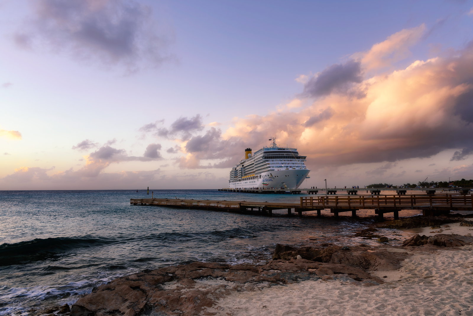 Cruise ship docked at a pier in Grand Turk, with turquoise water and palm trees.