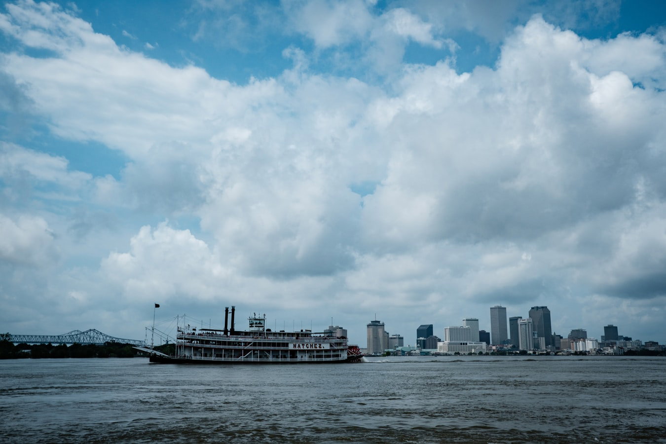 A large cruise ship docked at the New Orleans port with the city's historic buildings.