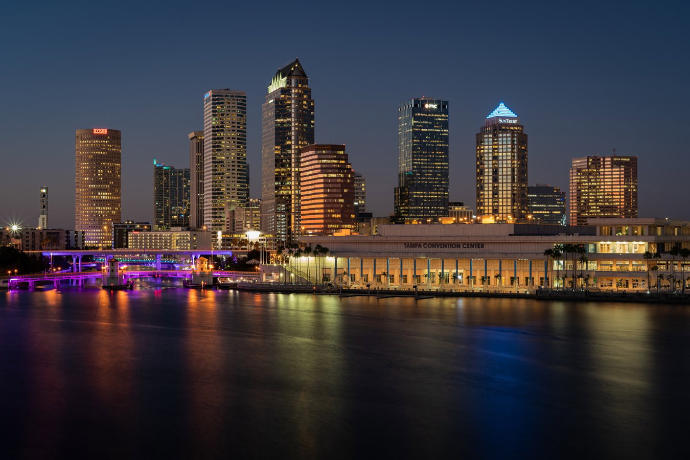 Cruise ship docked at a sunny port in Tampa, Florida, with city buildings.