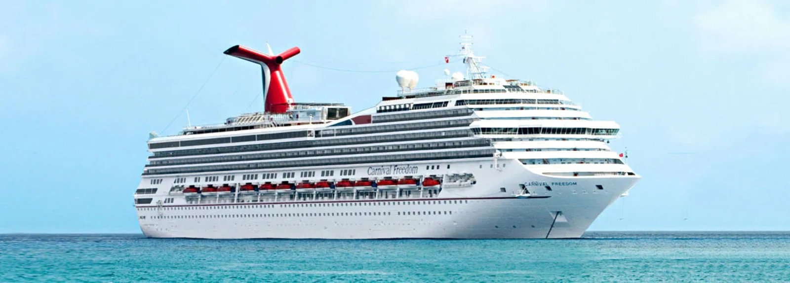 A large cruise ship sailing on blue waters under a clear sky, with passengers enjoying the deck.