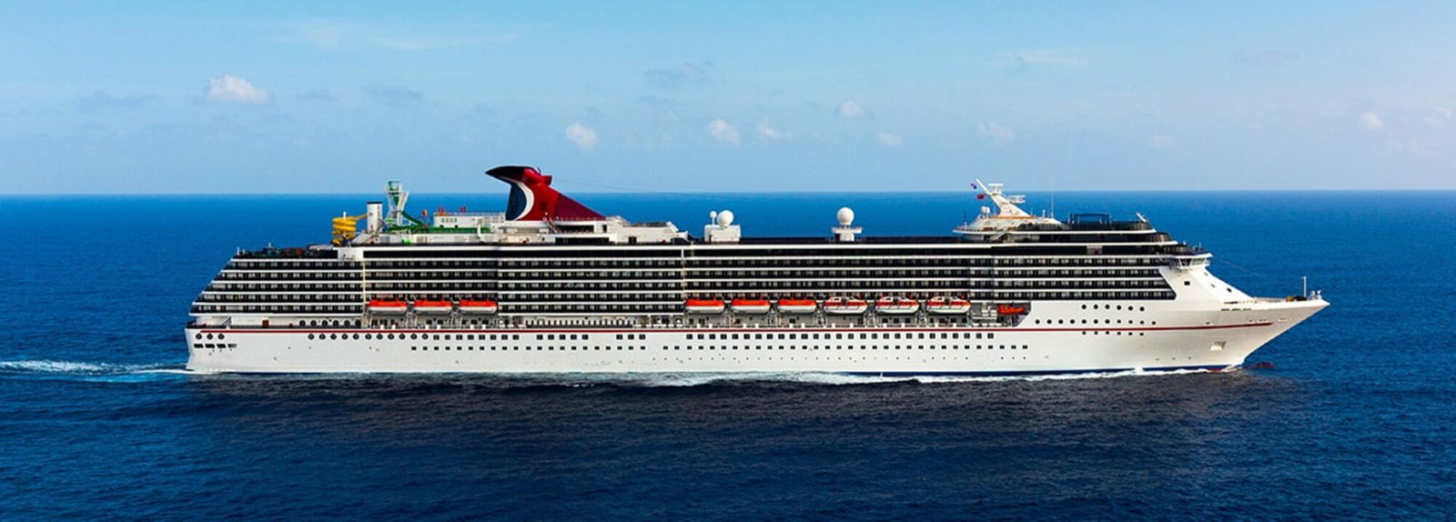 Carnival Miracle cruise ship sailing on the open ocean at sunset.