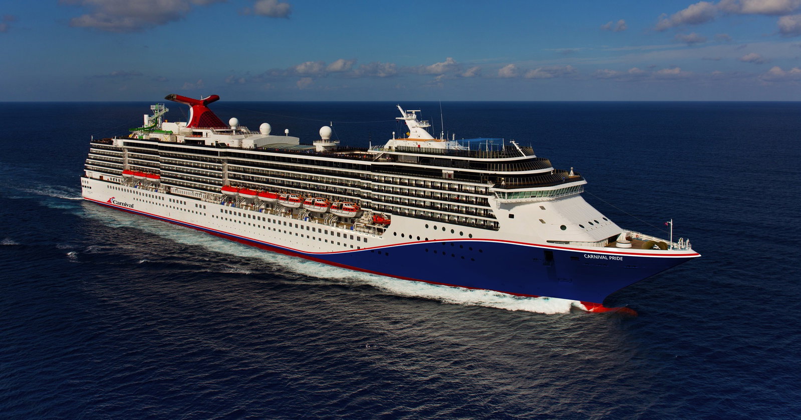 A vibrant Carnival cruise ship sailing on clear blue waters under a sunny sky.