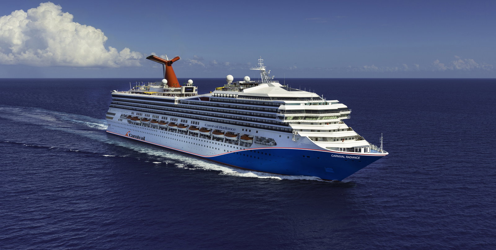Carnival Radiance cruise ship sailing on blue ocean waters under a clear sky.