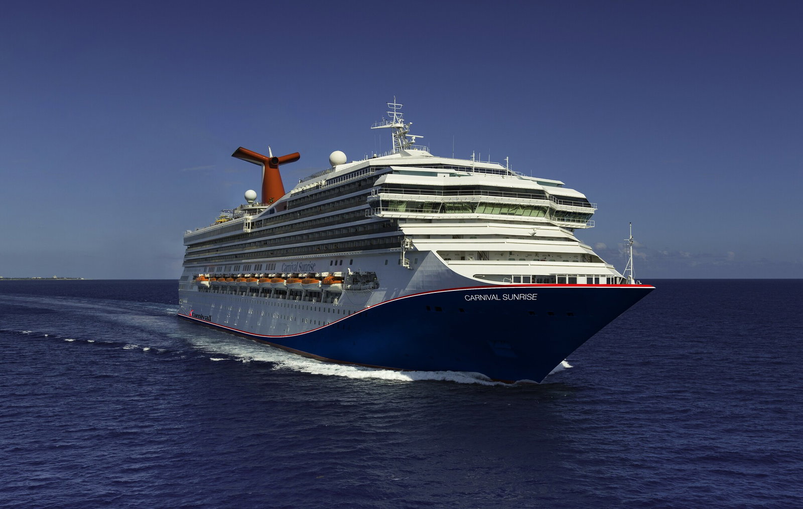 Carnival Sunrise cruise ship sailing on clear blue water under a sunny sky.
