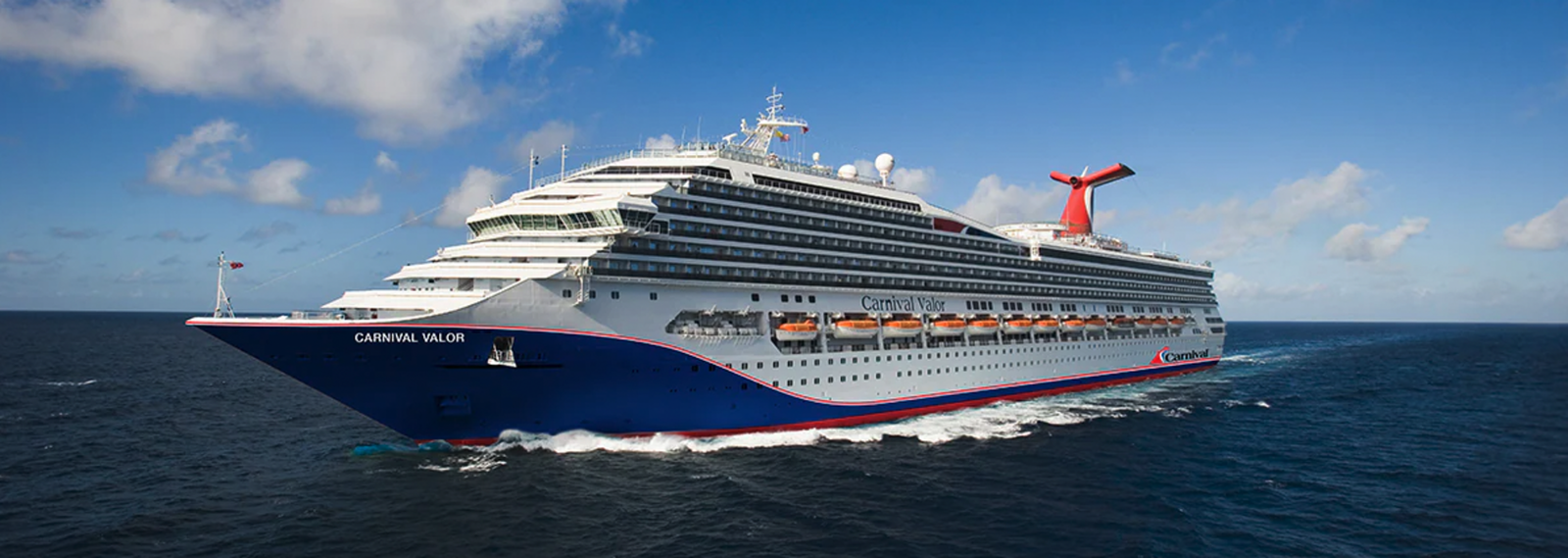 Carnival Valor cruise ship sailing on blue ocean waters under a sunny sky.