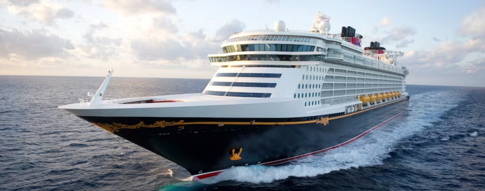 Disney Dream cruise ship sailing on blue ocean waters under a sunny sky.