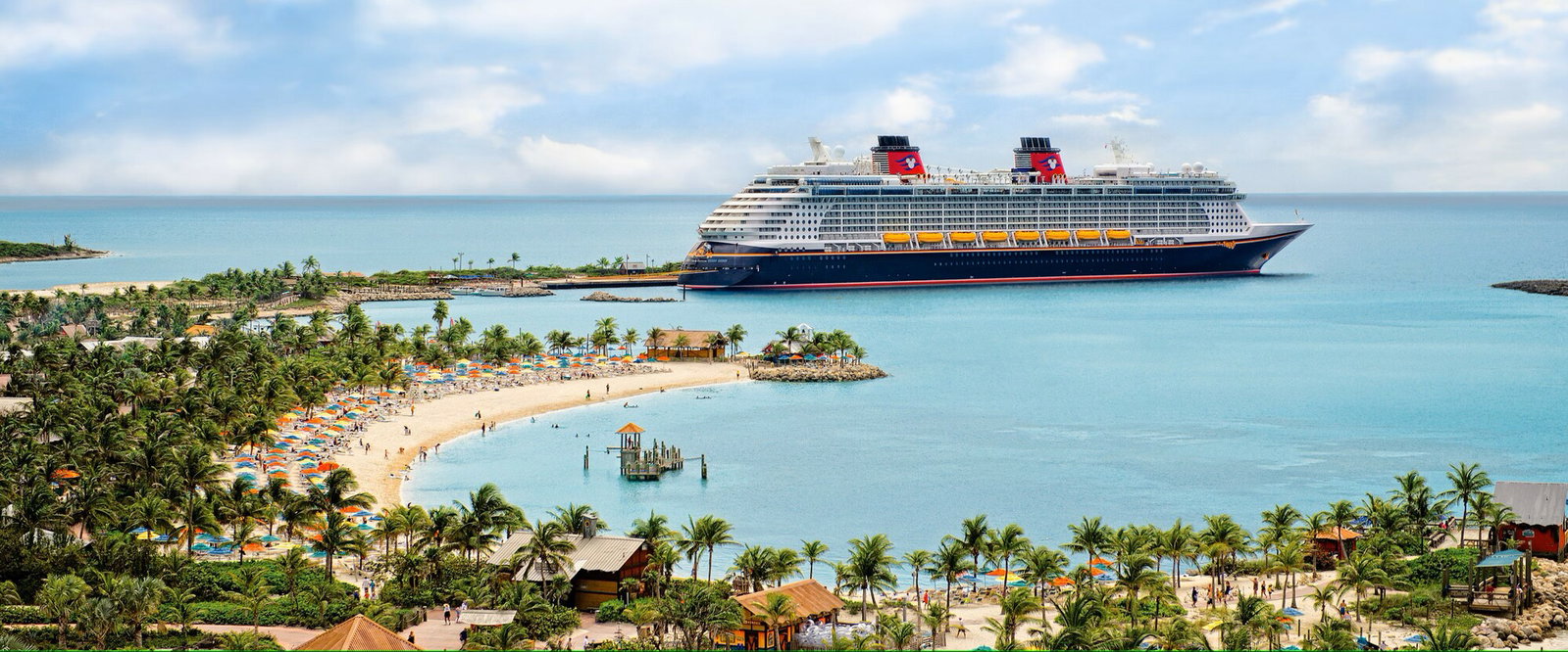 The Disney Fantasy cruise ship sailing on a clear blue ocean at sunset
