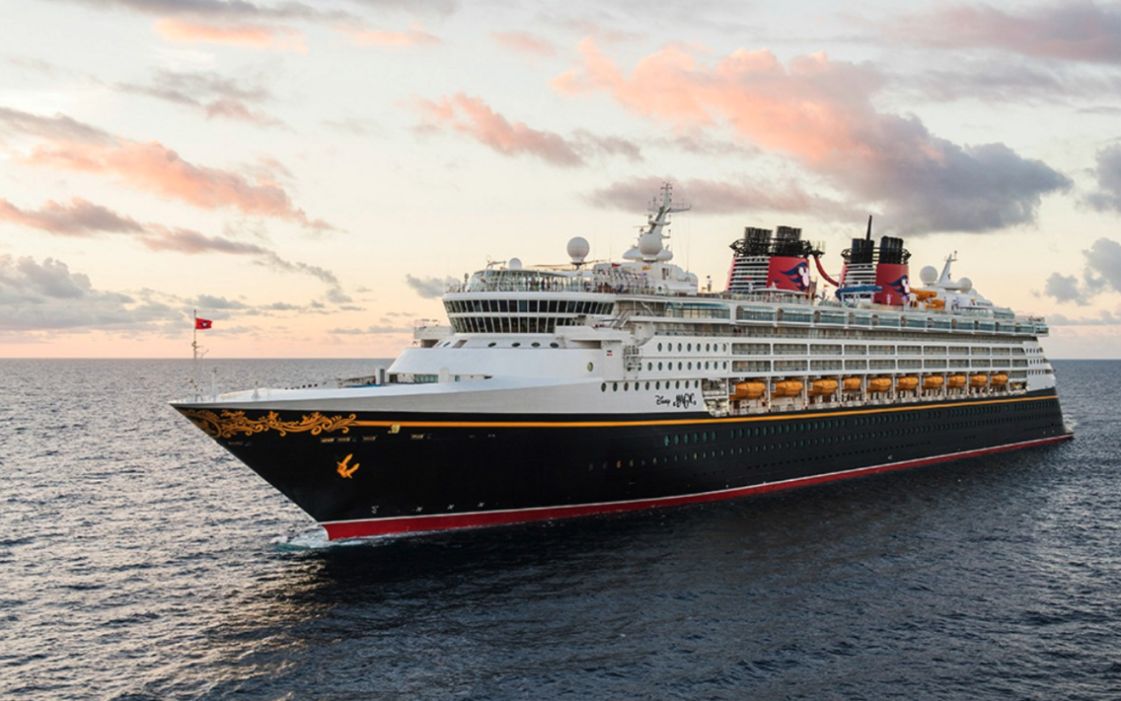 A large cruise ship with two red funnels sailing on calm blue waters.