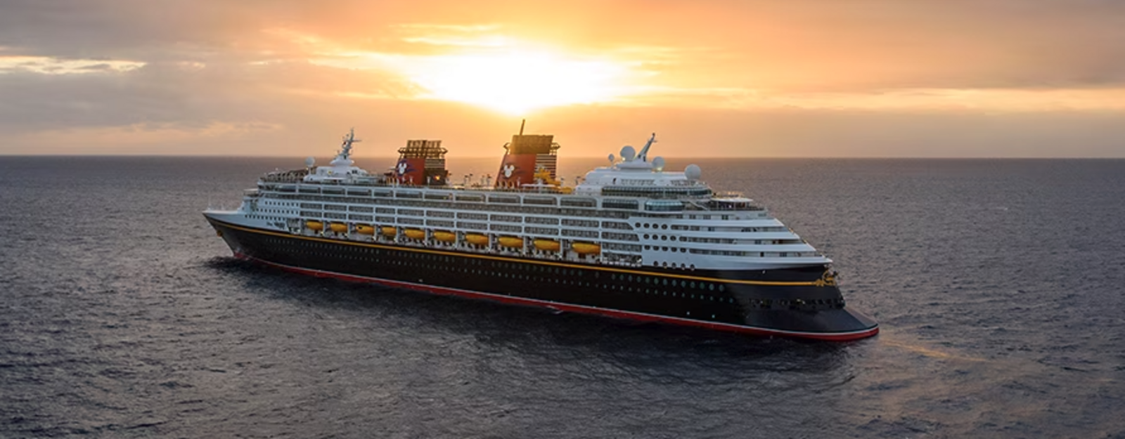 The Disney Wonder cruise ship sailing on calm, blue ocean waters.