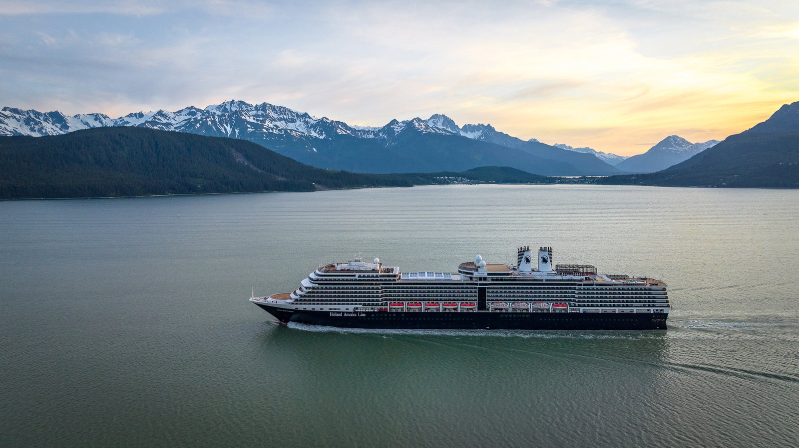 Nieuw Amsterdam cruise ship sailing through calm waters at sunset.
