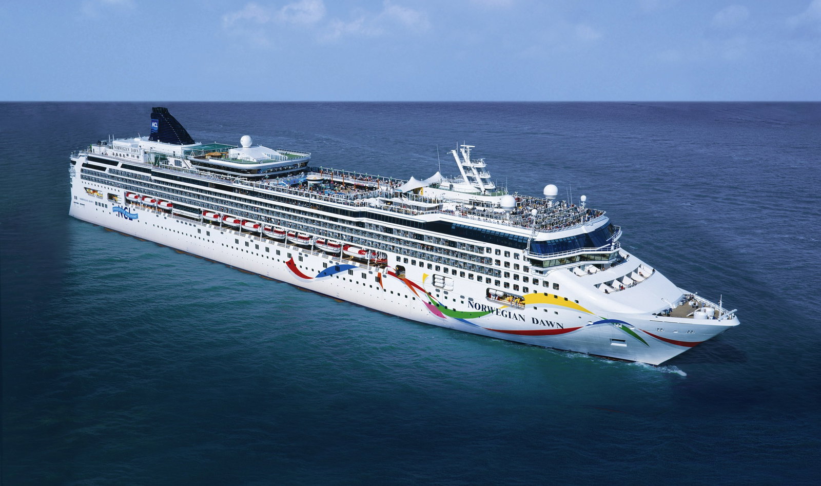Norwegian Dawn cruise ship sailing on calm waters at sunset.