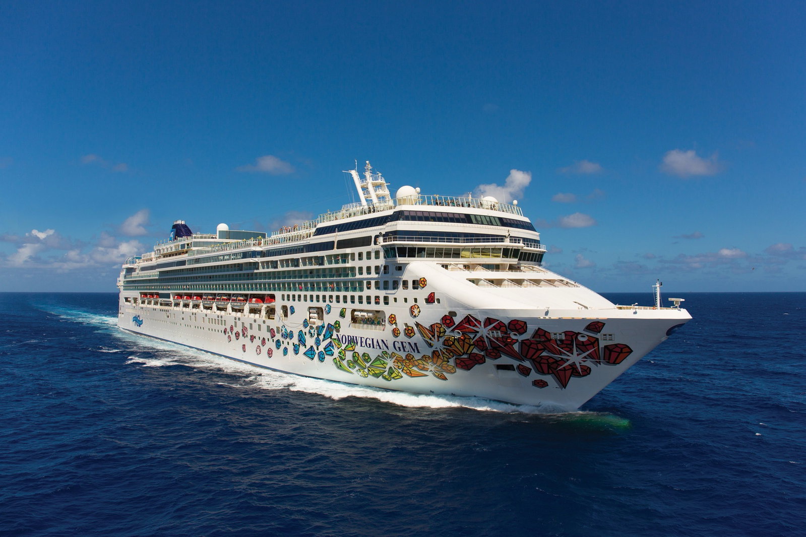Norwegian Gem cruise ship sailing on calm blue waters under a clear sky.