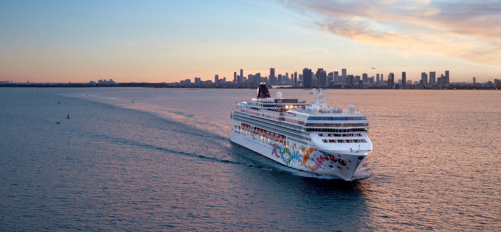 Cruise ship sailing on a clear blue ocean with a sunny sky.