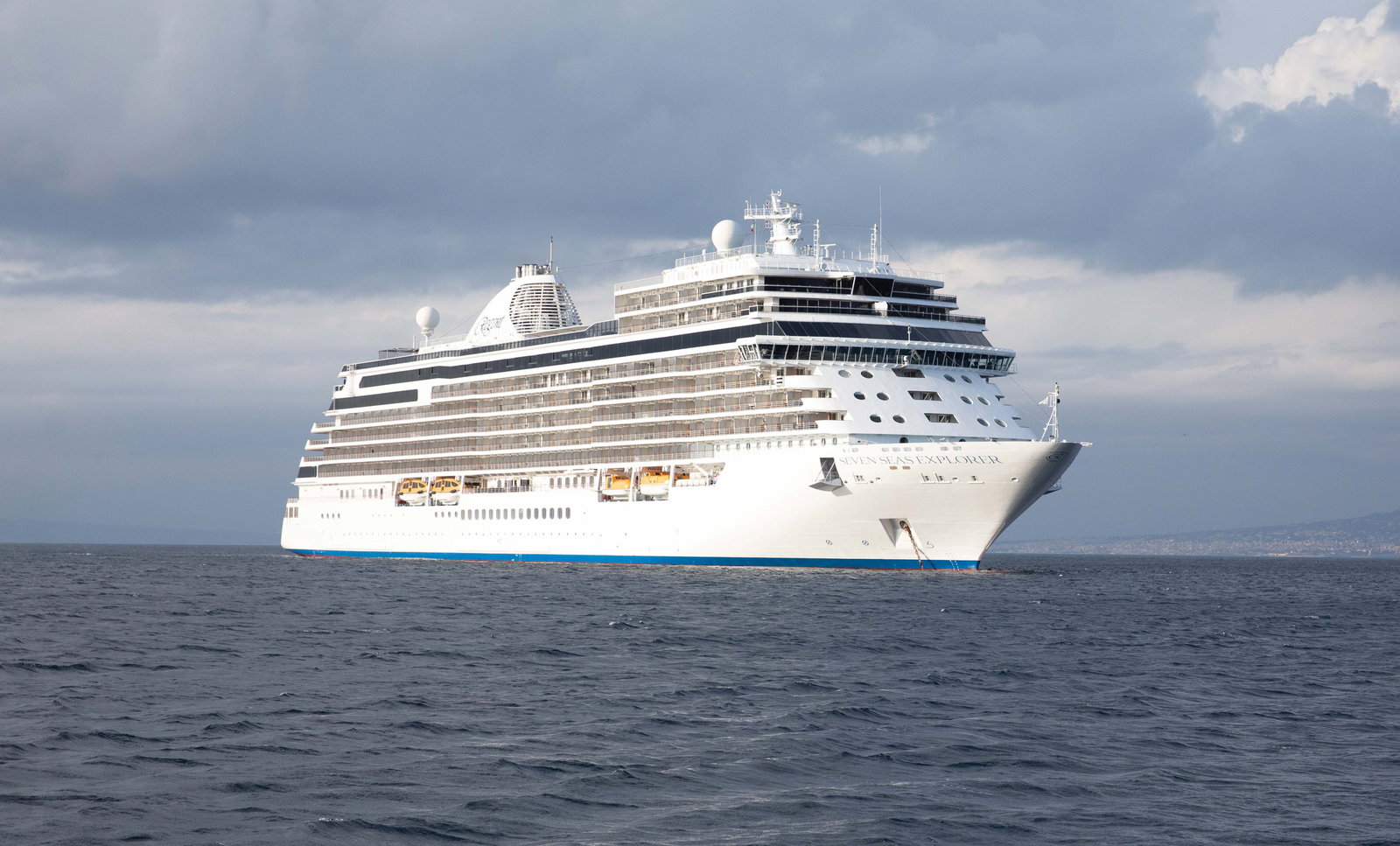 Luxurious cruise ship sailing on calm blue waters under a clear sky.