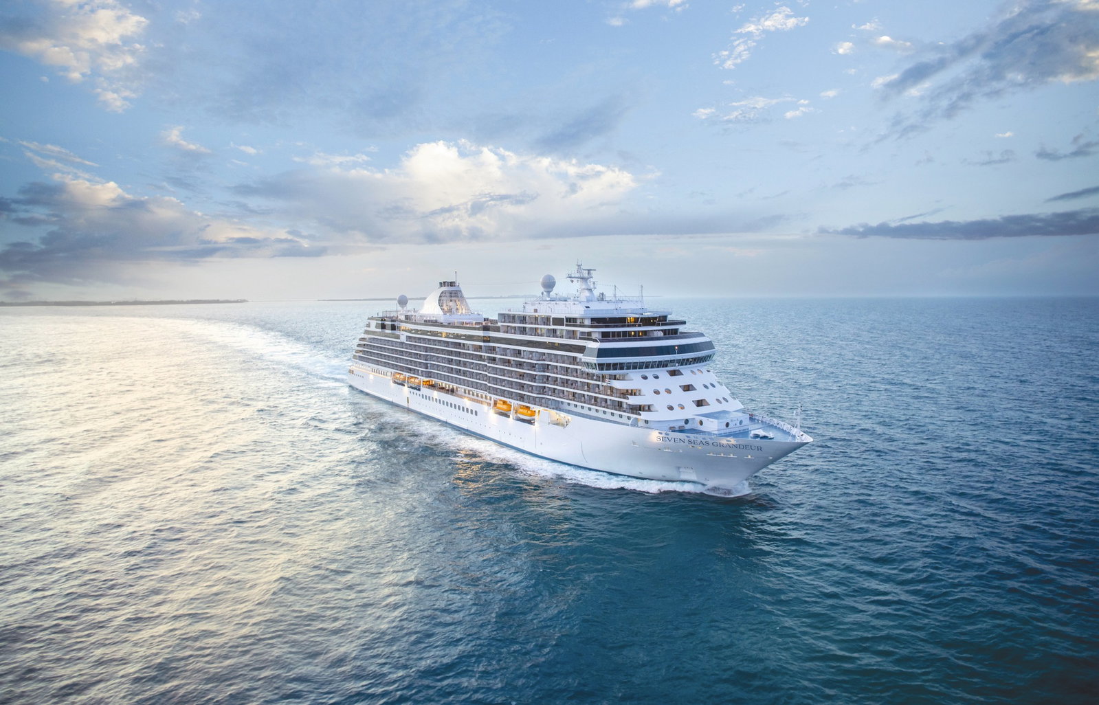 A luxury cruise ship sailing on calm blue waters under a clear sky.