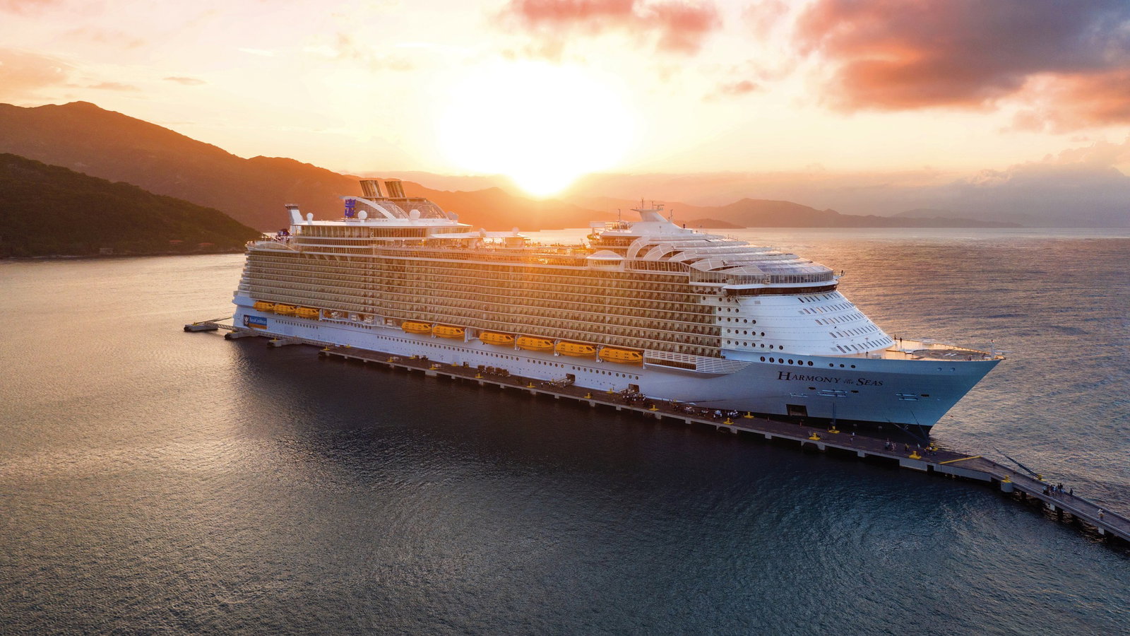 Harmony of the Seas ship sailing on blue ocean with families enjoying pool deck