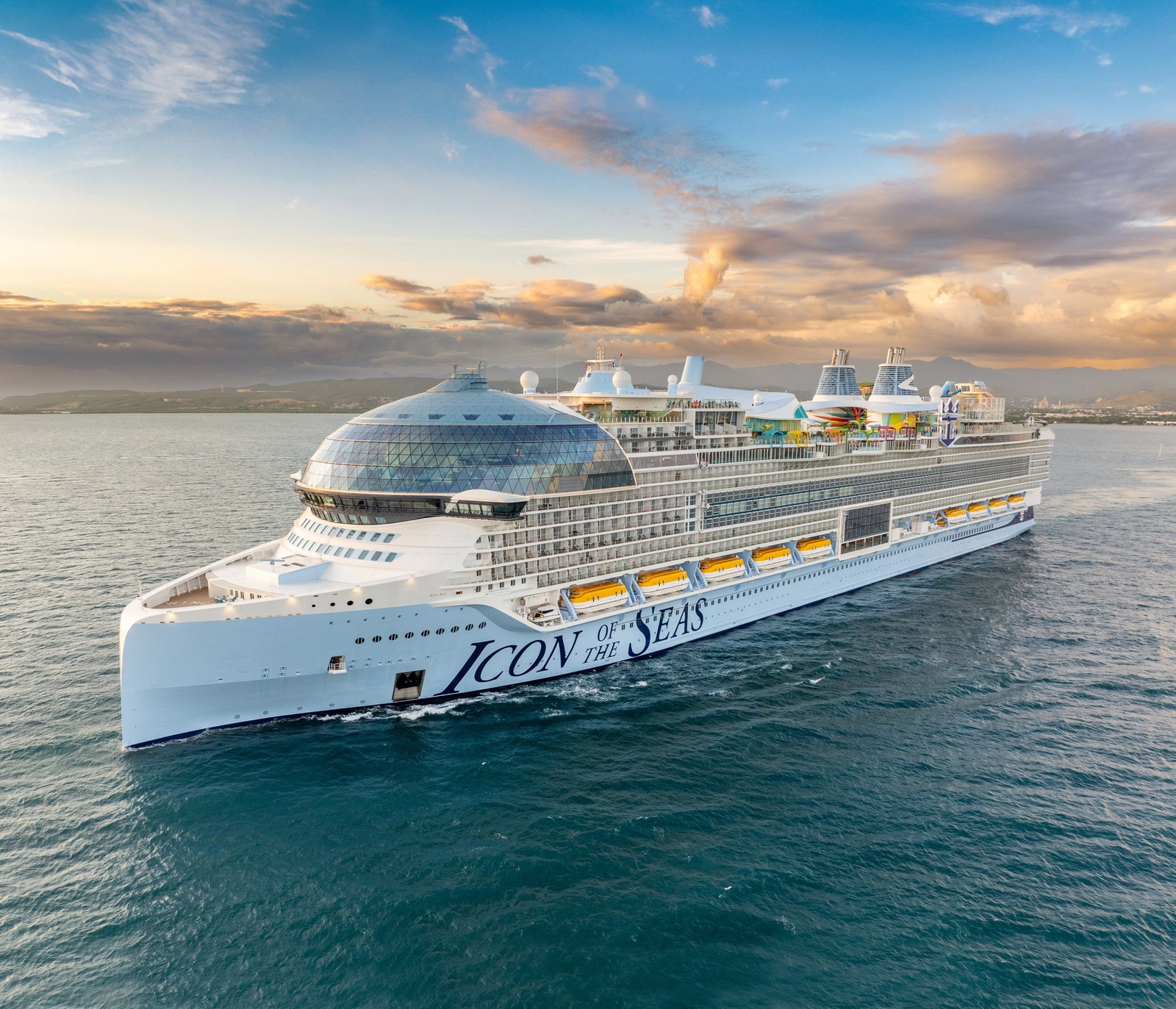 Aerial view of a large, vibrant cruise ship with multiple pools and water slides.