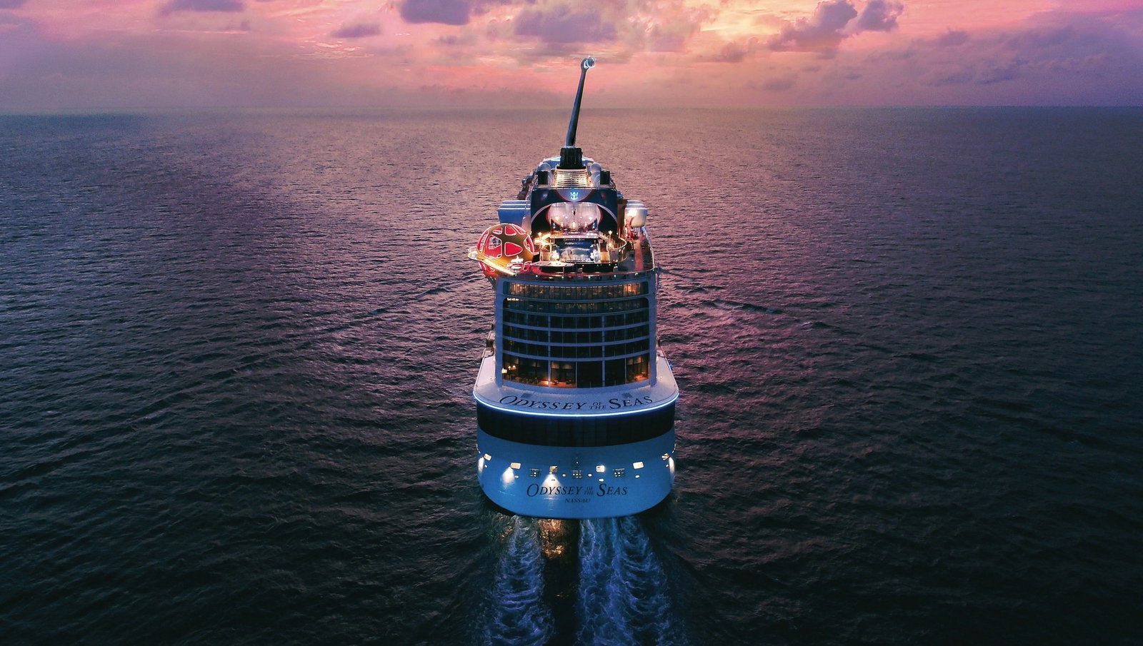 Aerial view of a vibrant cruise ship with pools, waterslides, and observation capsule at sea.