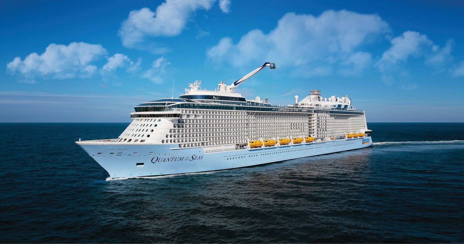Wide shot of Royal Caribbean's Quantum of the Seas sailing on calm blue waters under a clear sky.