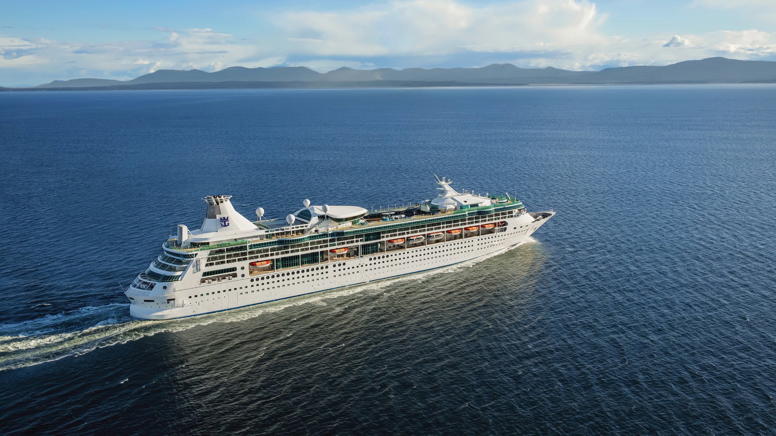 Rhapsody of the Seas cruise ship sailing on calm blue ocean waters under a clear sky.