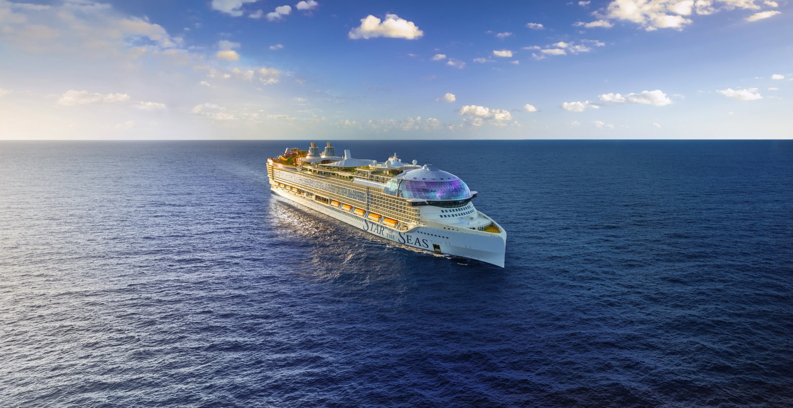 A large, modern cruise ship sailing on blue waters, with families enjoying deck activities.
