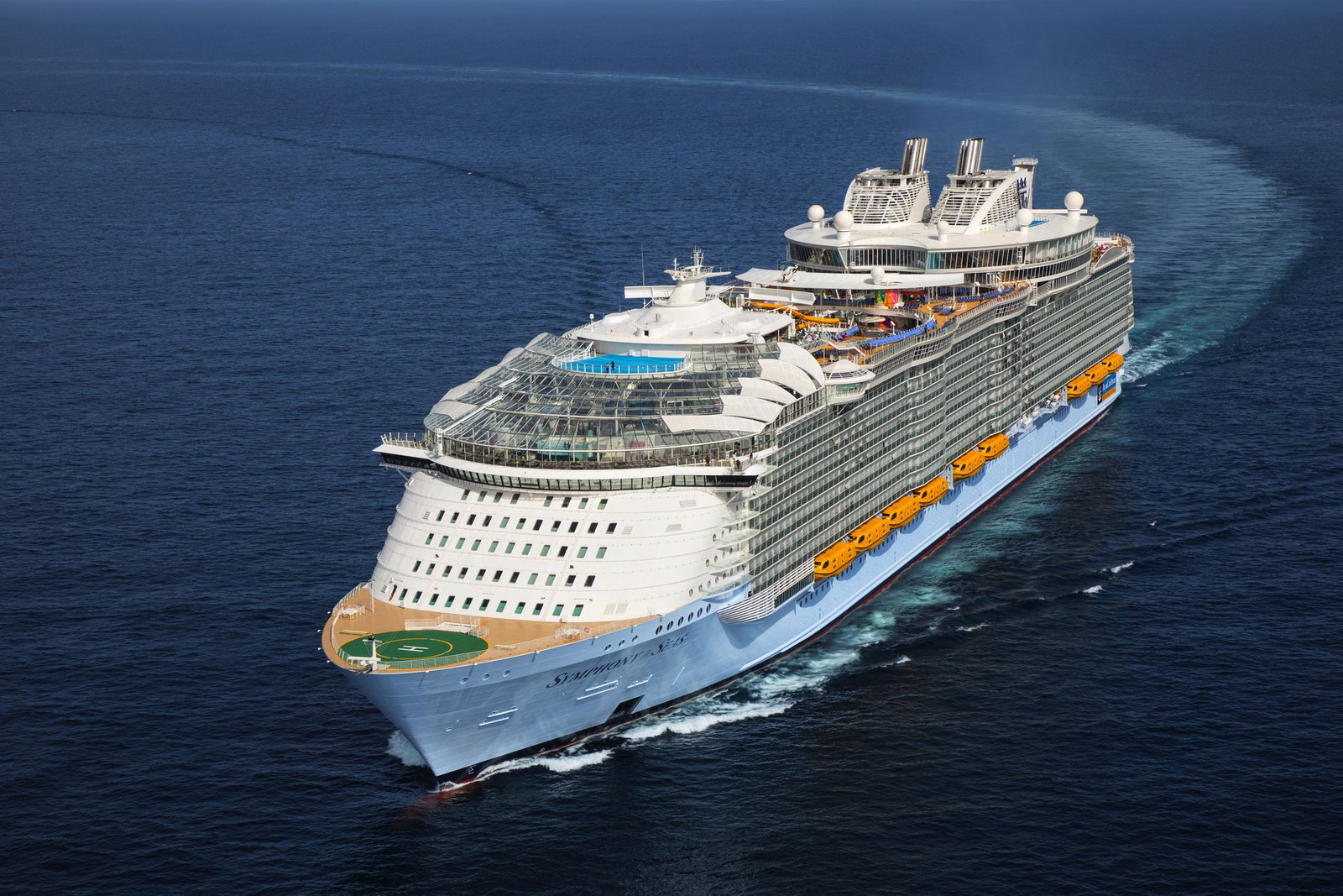 A large cruise ship sailing on blue ocean waters under a clear sky.