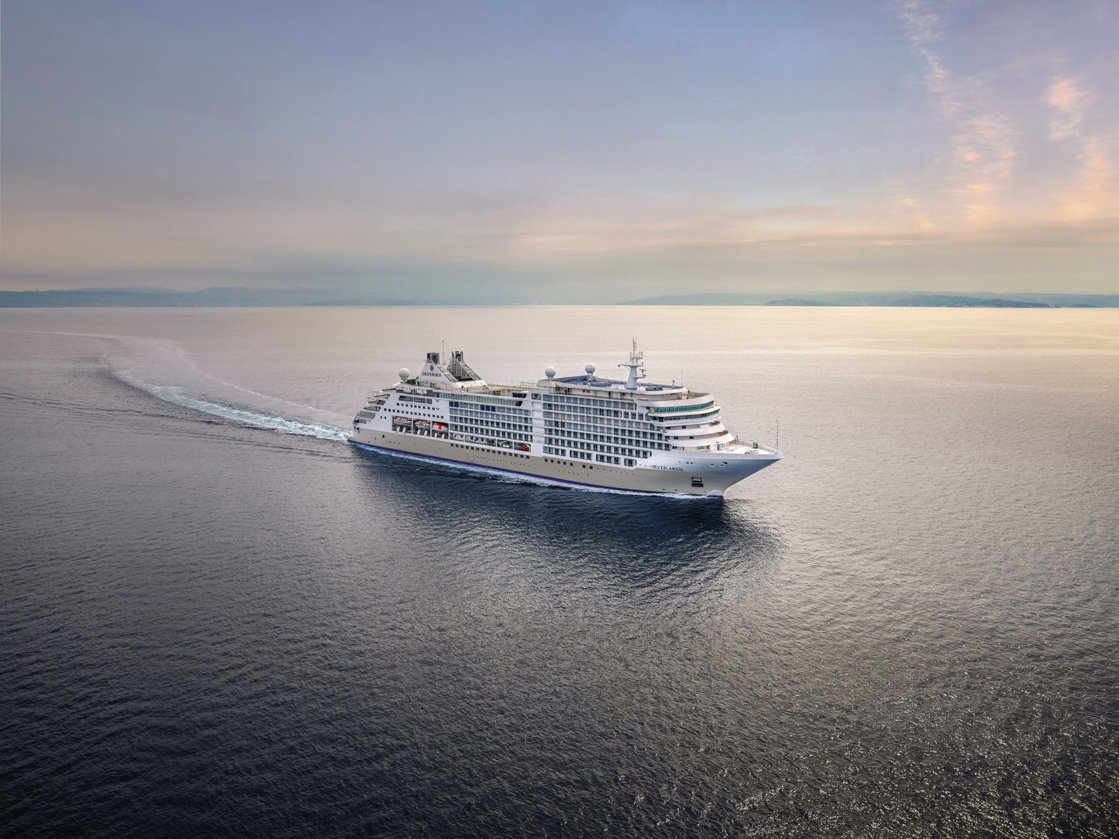 Luxurious cruise ship Silver Moon sailing on calm blue waters at sunset